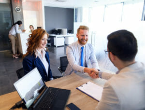 People sitting around desk shaking hands