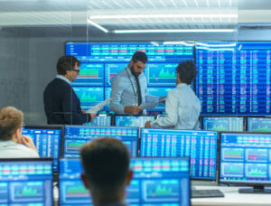 Men in stock trading room surrounded by ticker monitors